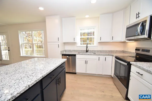 a kitchen with granite countertop sink stove and cabinets