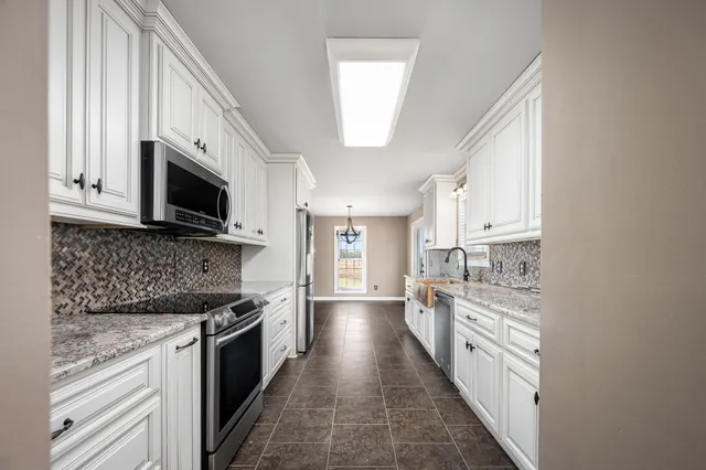 a kitchen with white cabinets and window
