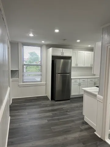 a kitchen with kitchen island wooden floors white appliances and cabinets