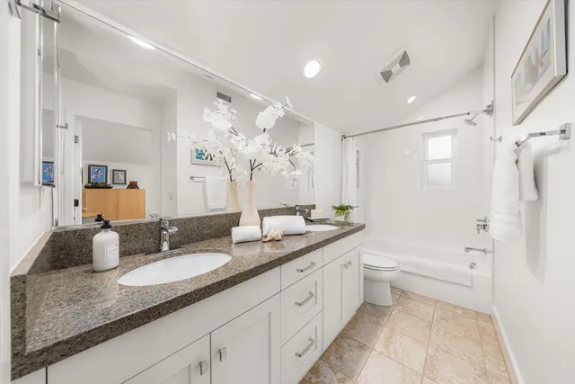 a bathroom with a granite countertop double vanity sink a mirror and a bathtub