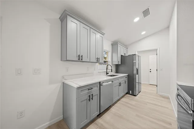 a large white kitchen with stainless steel appliances granite countertop a sink and cabinets with wooden floor