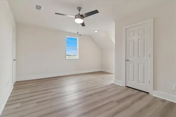 an empty room with wooden floor ceiling fan and window