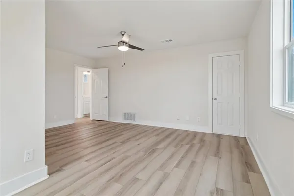 an empty room with wooden floor and windows