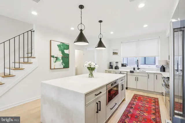 a kitchen with a stove a sink a center island and wooden floor