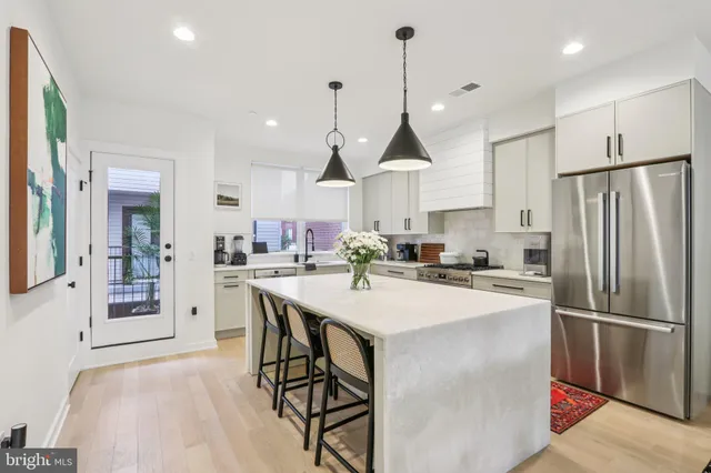 a kitchen with stainless steel appliances a refrigerator a oven a sink a stove and white cabinets