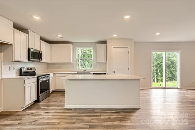a large kitchen with cabinets wooden floor and a window