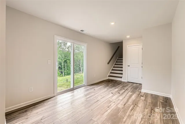a view of an empty room with wooden floor and stairs