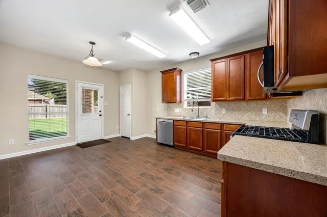 a kitchen with stainless steel appliances granite countertop a sink a stove cabinets and wooden floor
