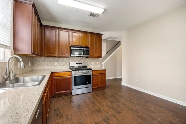 a kitchen with wooden floors a stove and a microwave