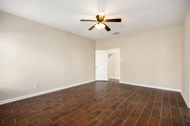 an empty room with a ceiling fan and carpet