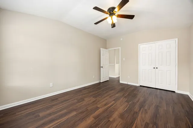 an empty room with wooden floor and a ceiling fan