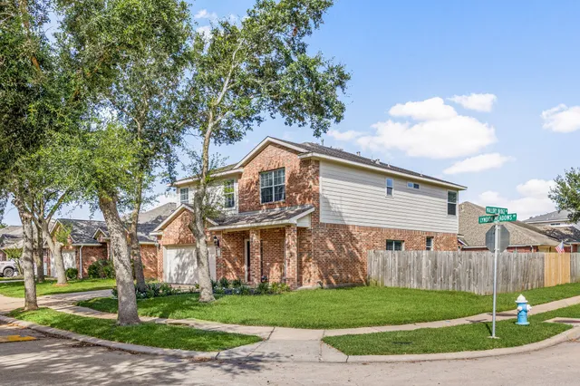 a view of a yard in front of a brick house with large windows