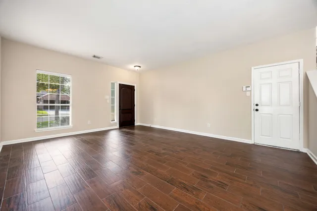 a view of an empty room with wooden floor and windows