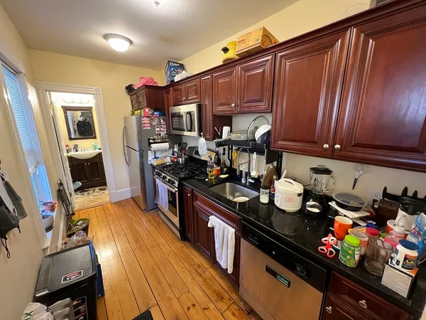a kitchen with granite countertop lots of clutter and stainless steel appliances
