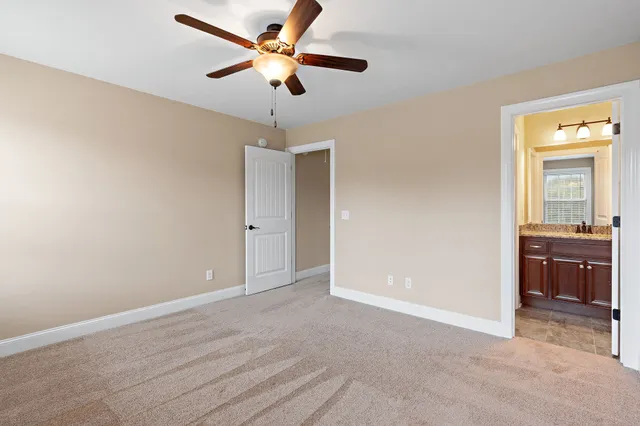 an empty room with a ceiling fan and a carpet