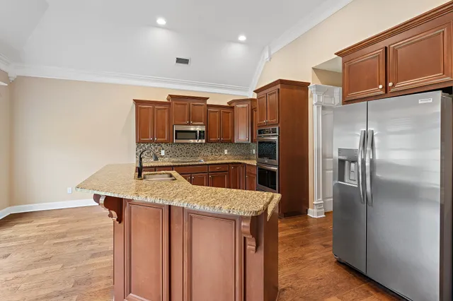 a kitchen with stainless steel appliances granite countertop a refrigerator a sink and a stove