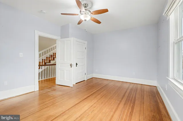 a view of empty room with wooden floor and fan