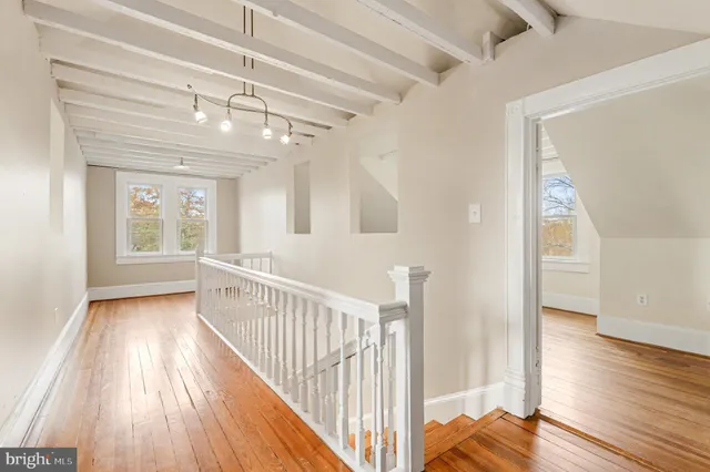 a view of a hallway with wooden floor and a bathroom