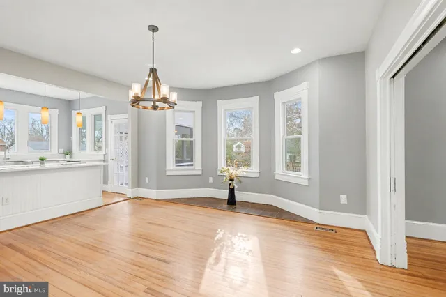 a kitchen with stainless steel appliances granite countertop a stove a sink dishwasher a refrigerator and white cabinets with wooden floor