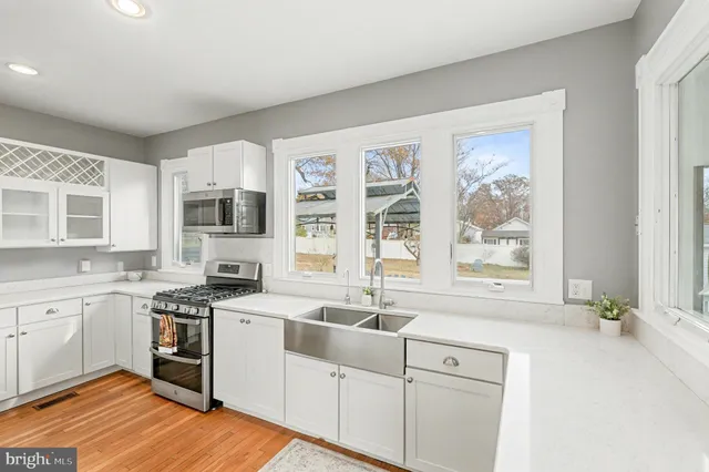 an empty room with wooden floor chandelier fan and windows