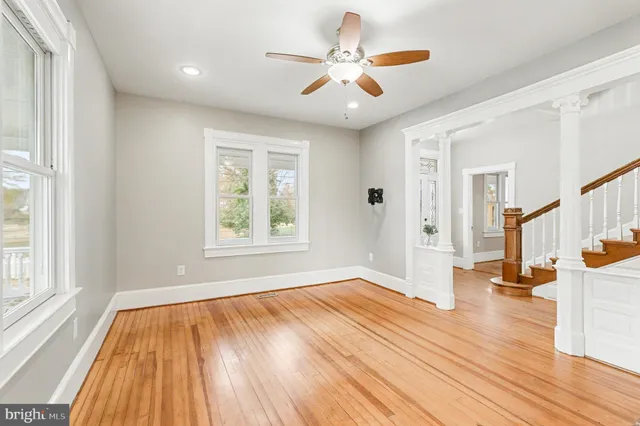 a view of empty room with wooden floor and fan
