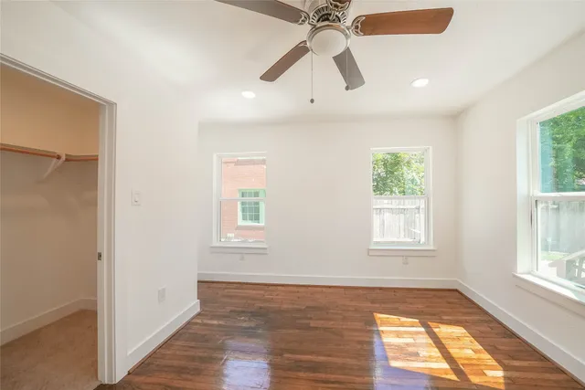 a view of empty room with wooden floor and fan