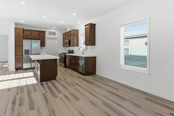 a large kitchen with stainless steel appliances kitchen island granite countertop a large counter top and view of living room