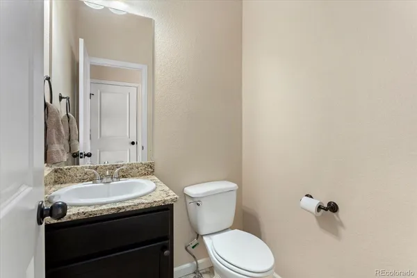 a bathroom with a granite countertop toilet sink and mirror