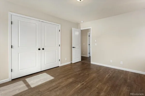an empty room with wooden floor cabinet and windows
