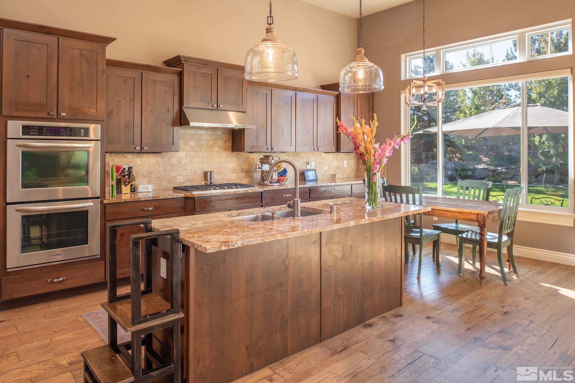 3910 Nature Trail Reno, NV 89511 - Photo 8 of 29 a kitchen with kitchen island granite countertop a stove top oven a sink a dining table and chairs with wooden floor