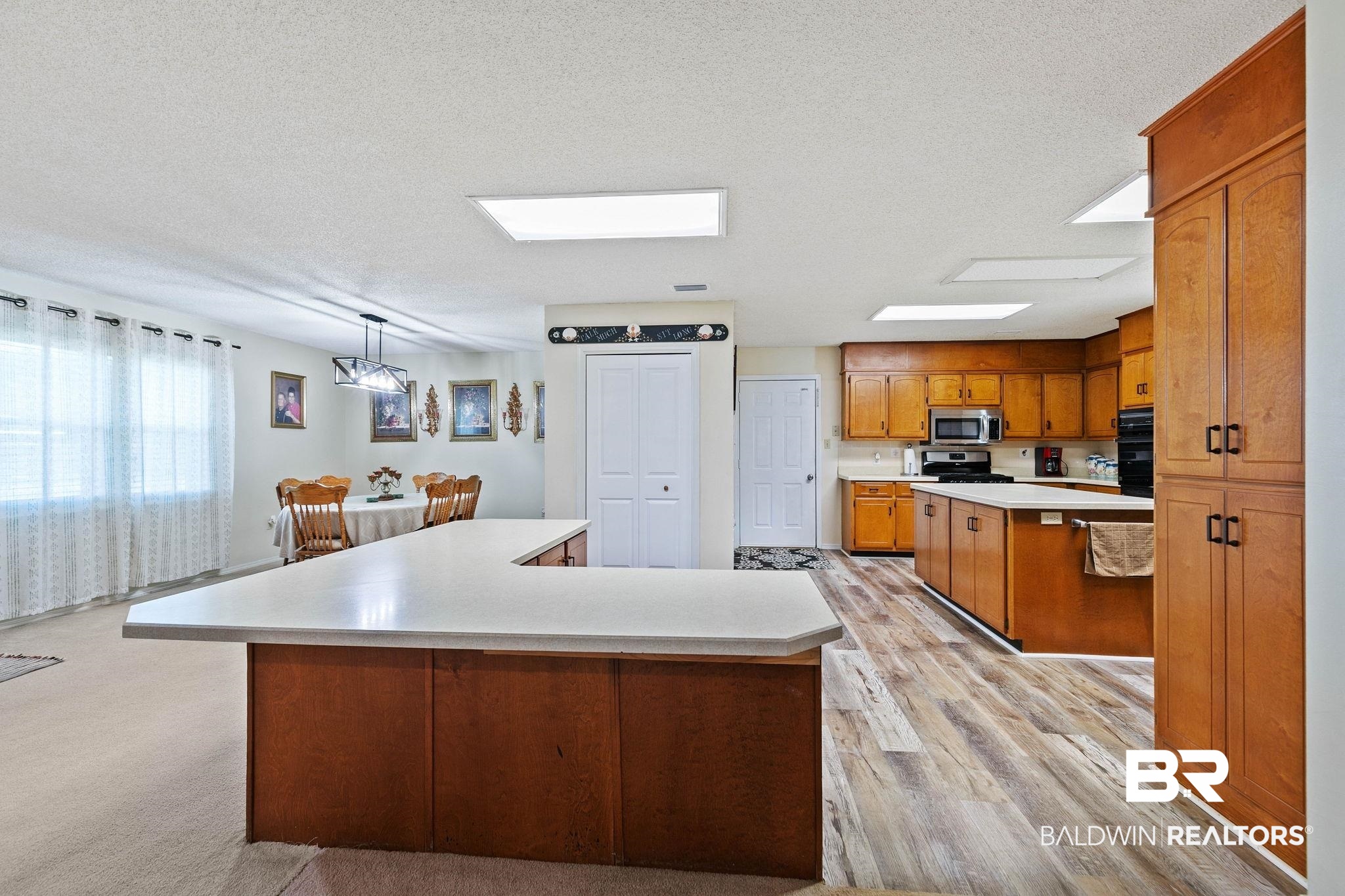 1510 South Juniper Street Foley, AL 36535 - Photo 12 of 36 Kitchen featuring a kitchen island, light countertops, brown cabinets, hanging light fixtures, and a textured ceiling