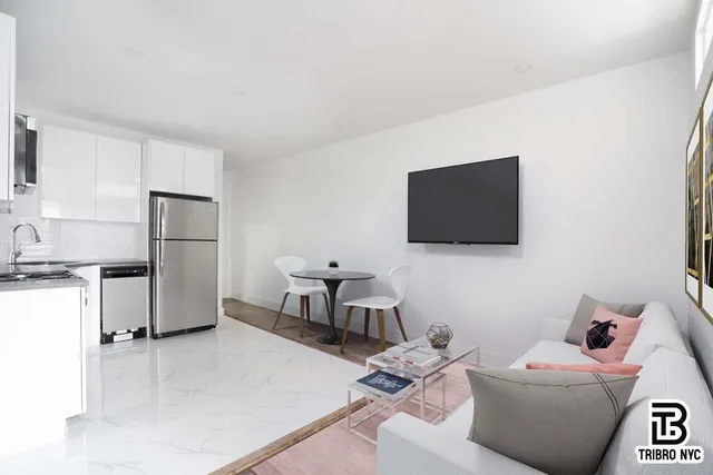 a living room with furniture a flat screen tv and a refrigerator