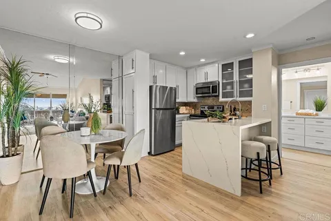 a kitchen with stainless steel appliances a dining table chairs refrigerator and sink