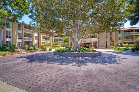 a front view of a building with trees and plants
