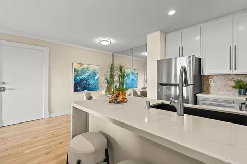 a kitchen with a sink a refrigerator and wooden floor