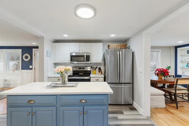 a kitchen with kitchen island a refrigerator wooden floor and cabinets