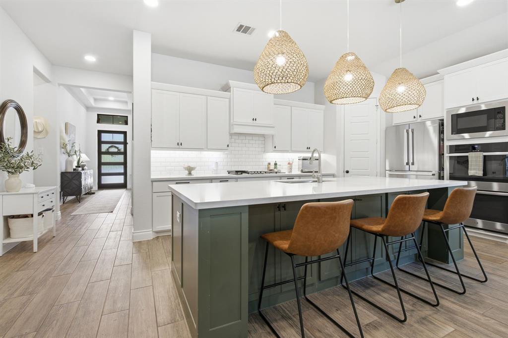 904 Fallbrook Avenue Denton, TX 76210 - Photo 11 of 30 a kitchen with stainless steel appliances granite countertop a table chairs sink and cabinets