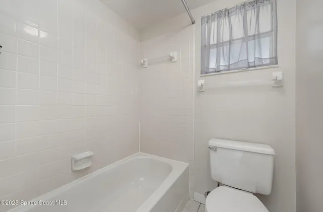a white toilet sitting next to a bath tub