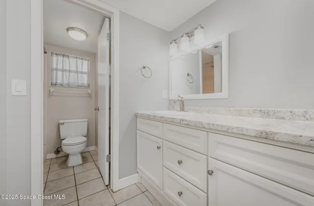 a bathroom with a granite countertop toilet sink and mirror