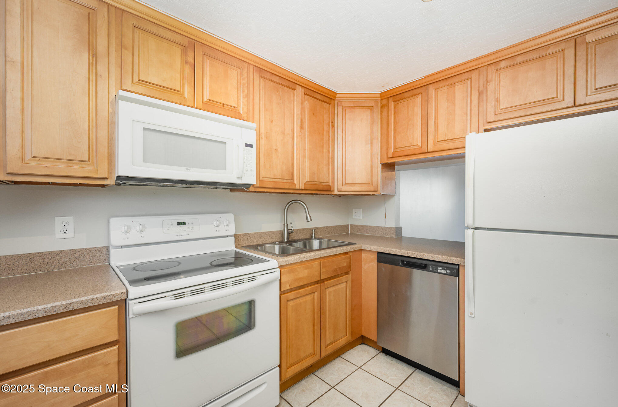 2935 Thrush Drive, Unit 144 Melbourne, FL 32935 - Photo 2 of 17 a kitchen with a sink dishwasher a refrigerator and cabinets with wooden floor