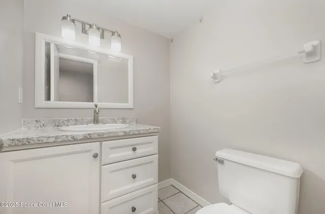 a bathroom with a granite countertop toilet sink and mirror