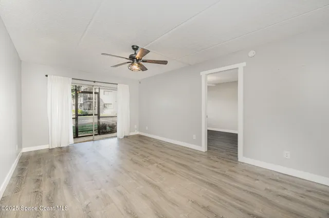 a view of an empty room with a window and wooden floor