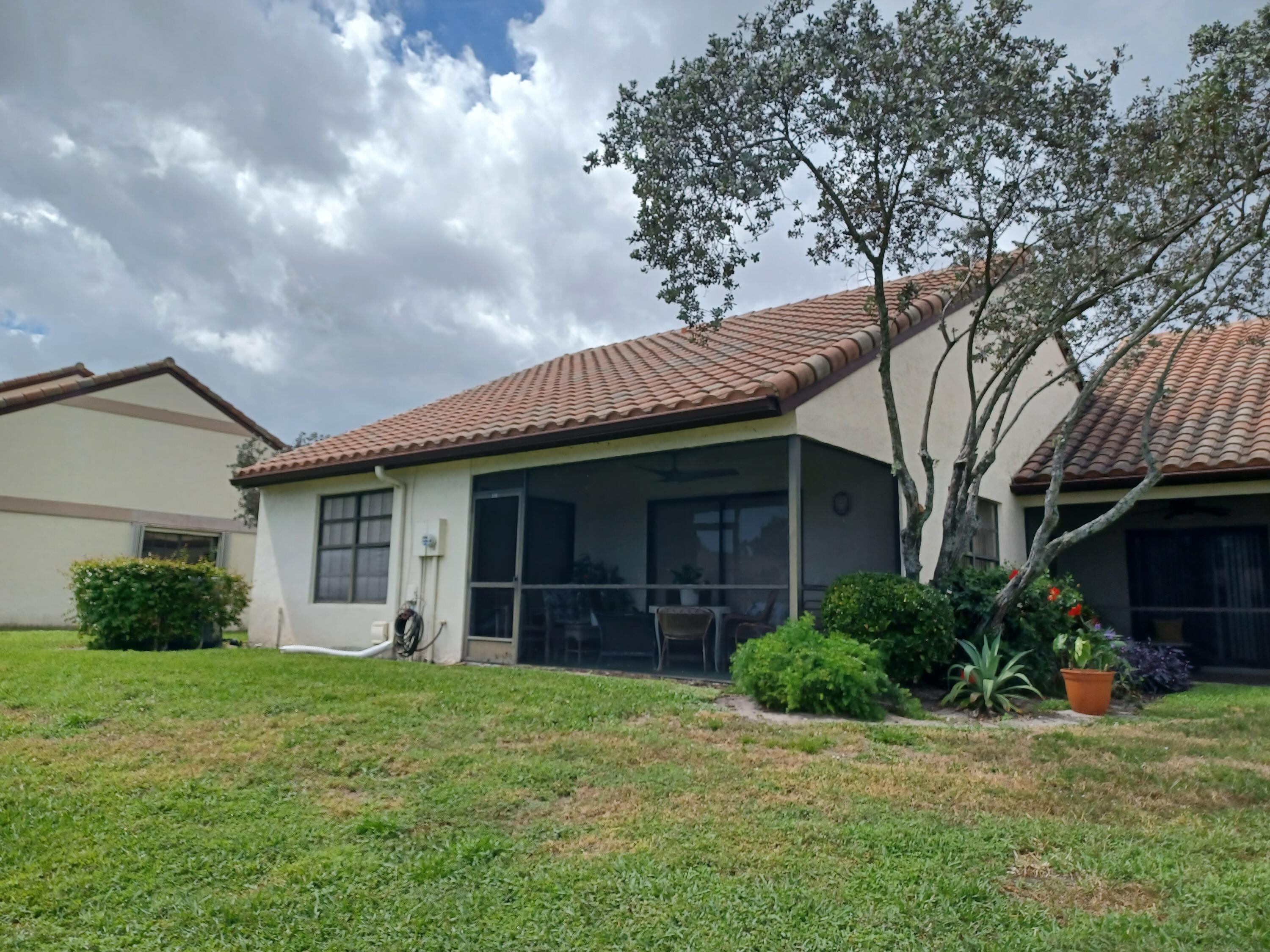 338 Eastwood Terrace Boca Raton, FL 33431 - Photo 6 of 31 a view of a house with brick walls and a yard with potted plants