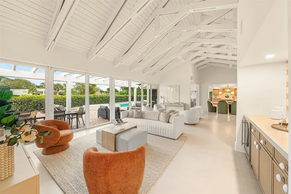 a living room with furniture large windows and wooden floor