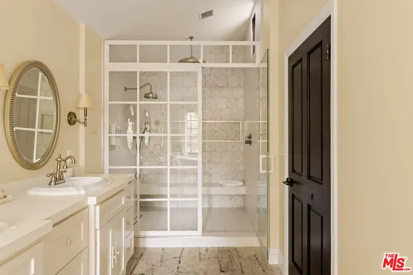 a bathroom with a granite countertop sink a mirror and a shower