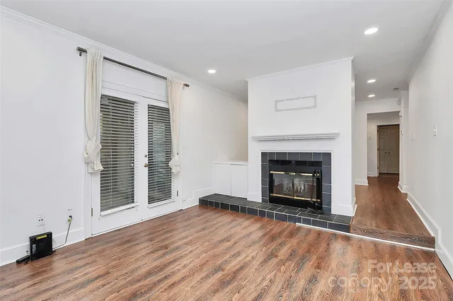 an empty room with wooden floor fireplace and windows