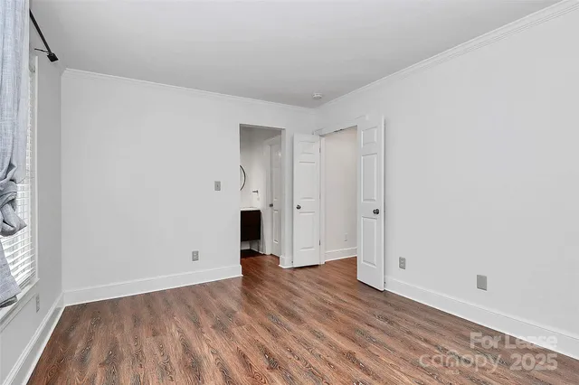 a view of empty room with wooden floor and white walls