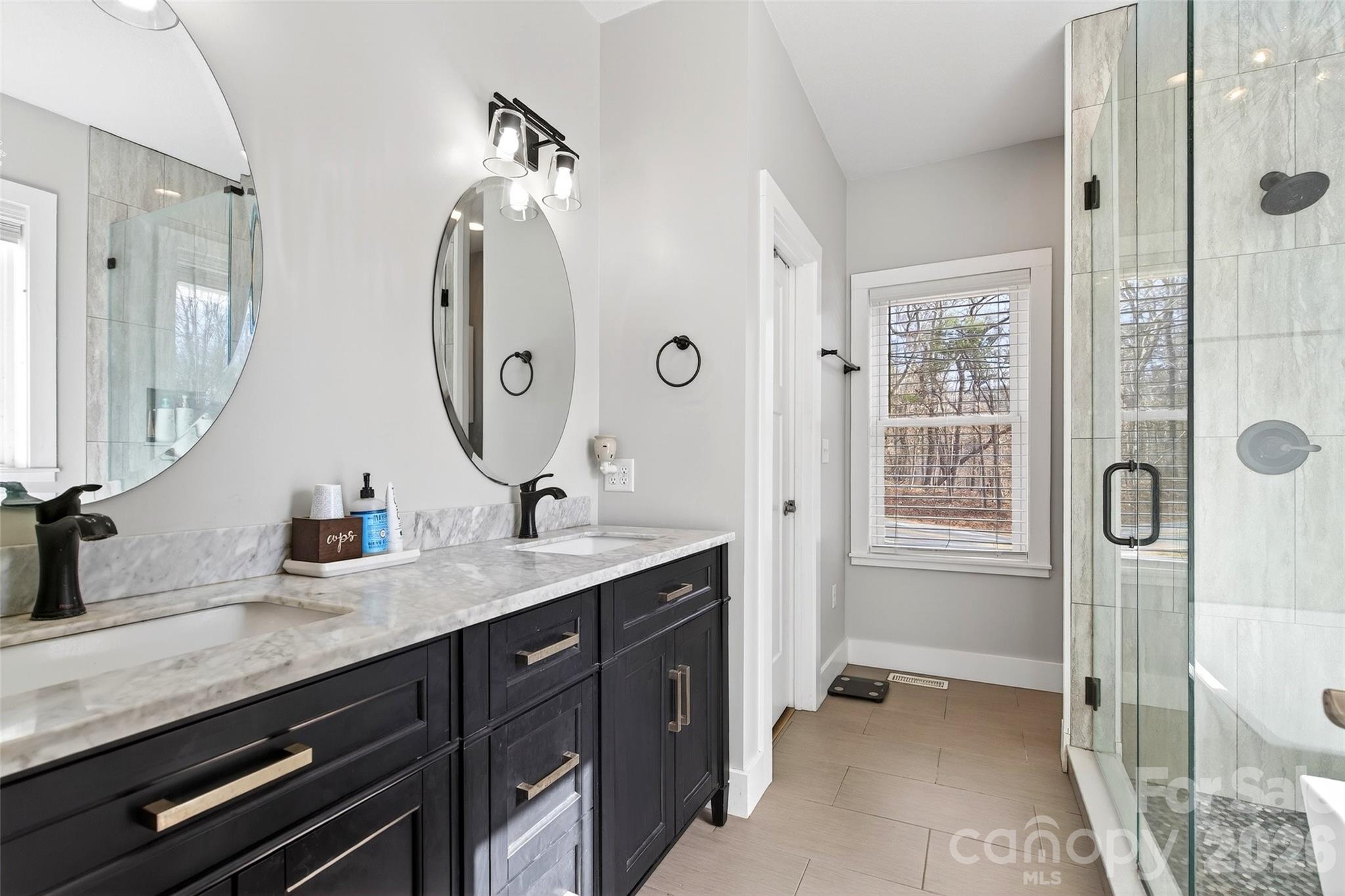 135 Ridge Road Candler, NC 28715 - Photo 16 of 40 a spacious bathroom with a granite countertop sink a mirror a vanity and a shower