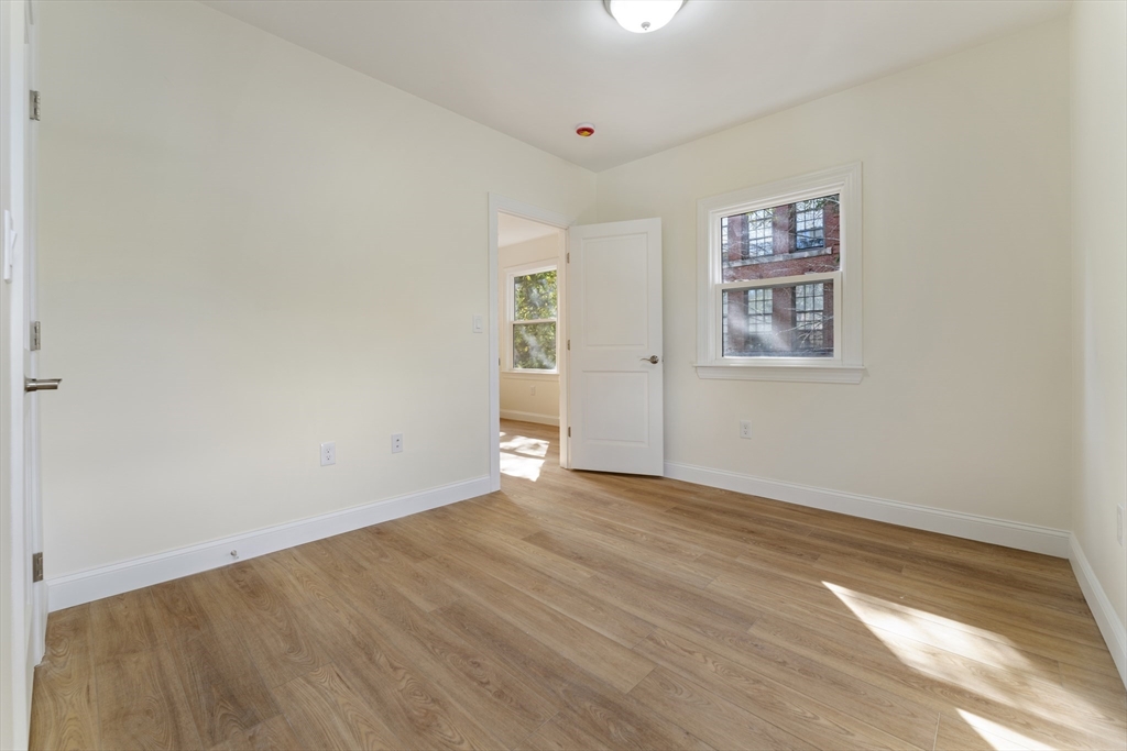 27 Perrin Street, Unit 1 Boston, MA 02119 - Photo 11 of 22 an empty room with wooden floor and windows