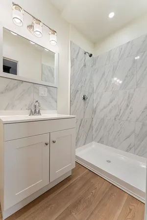 a bathroom with a sink vanity granite tub shower and a mirror